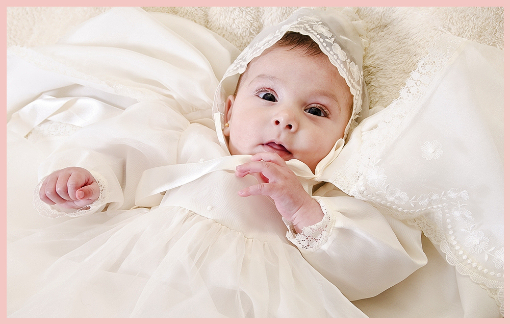 Malá holčička v bílých šatech na křtu